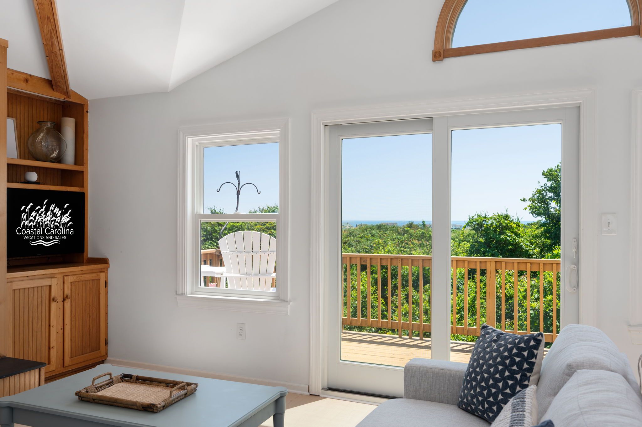 A spacious living area with a large sliding glass door leading to a deck with a view of the ocean.
