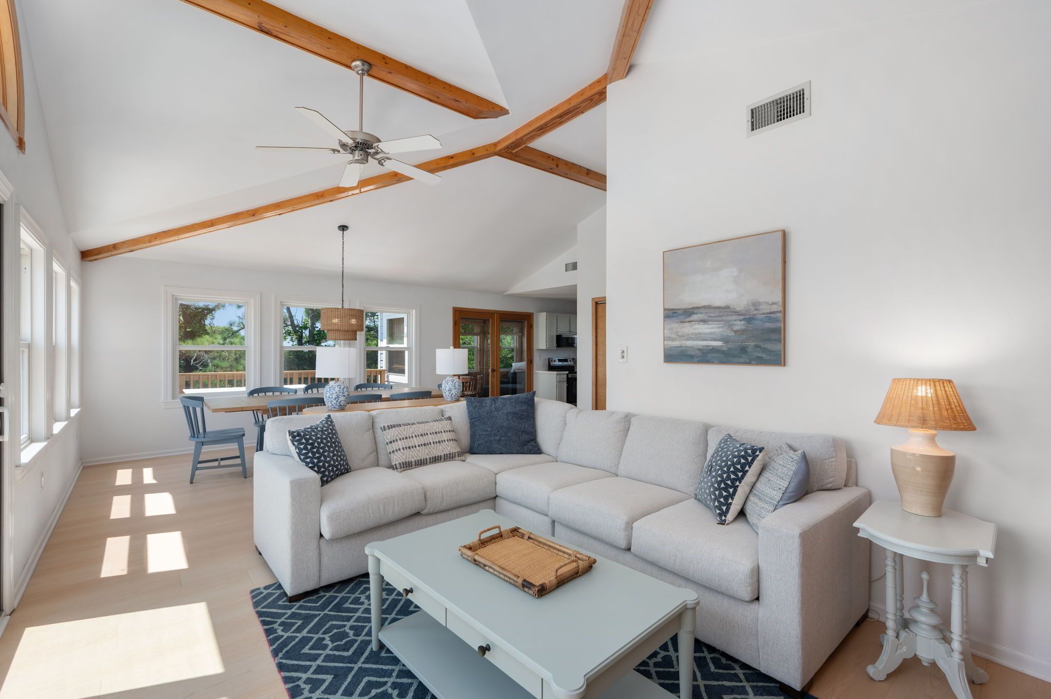 A spacious living room with a large sectional sofa, a coffee table, and a dining area with a table and chairs.