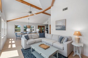 A spacious living room with a large sectional sofa, a coffee table, and a dining area with a table and chairs.
