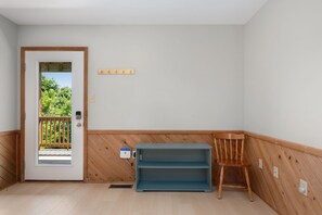 Ein Zimmer mit Holztür, die auf einen Balkon führt, einem blauen Regal und einem Holzstuhl.
