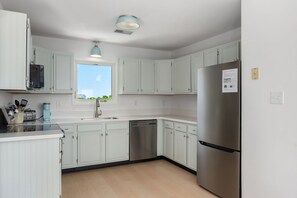 Uma cozinha moderna com armários em tons claros, eletrodomésticos de aço inoxidável e uma janela que proporciona iluminação natural.