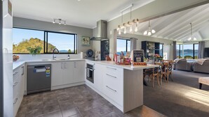 A modern kitchen with a central island, large windows, and a view of the outdoors.