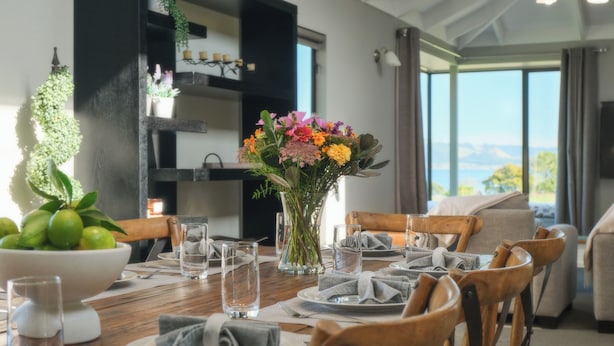 A dining table set with plates, glasses, and a centerpiece of flowers.