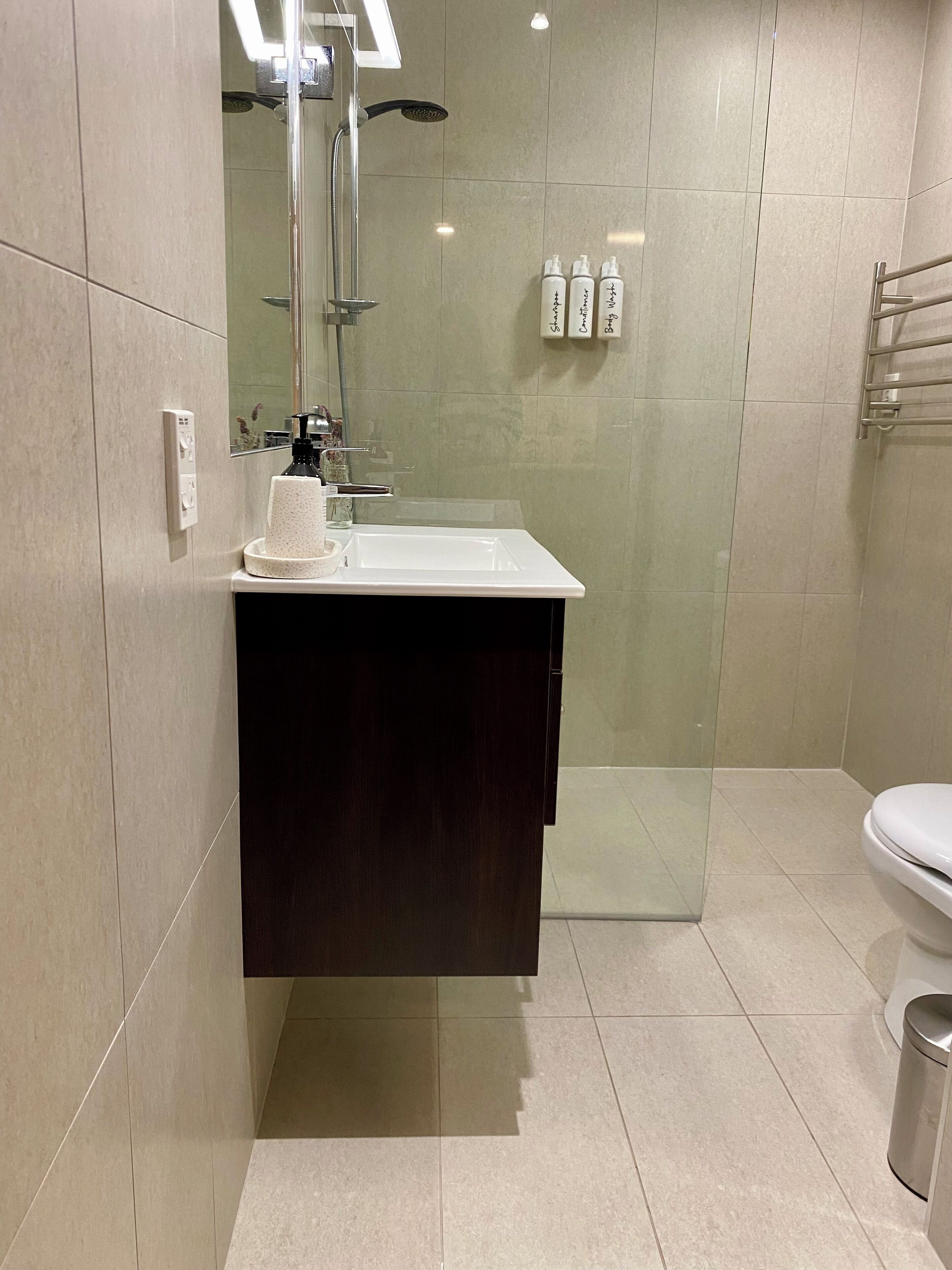 Une salle de bain moderne avec une douche à parois de verre, un lavabo blanc et des toilettes.