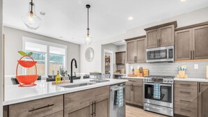 A modern kitchen with a central island, stainless steel appliances, and wooden cabinetry.
