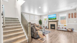 A spacious living room with a fireplace, a television, and a staircase.