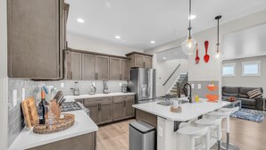 A modern kitchen with a central island, stainless steel appliances, and a dining area with bar stools.