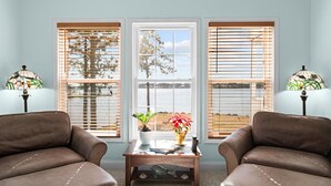 A room with two leather sofas, a wooden coffee table, and a view through a central window. - Carolina Breeze - Your Perfect Getaway! (Merritt)
