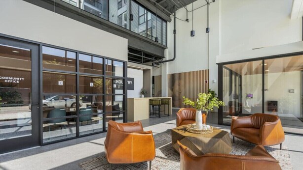 A modern lobby with leather seating, a coffee table, and a large window overlooking the street.