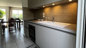 A modern kitchen with a large island, built-in appliances, and a dining area with a view. - 2-Bedroom holidays Cottage with 2 Terrace, Air Conditioning  et  Parking (CANET PLAGE)