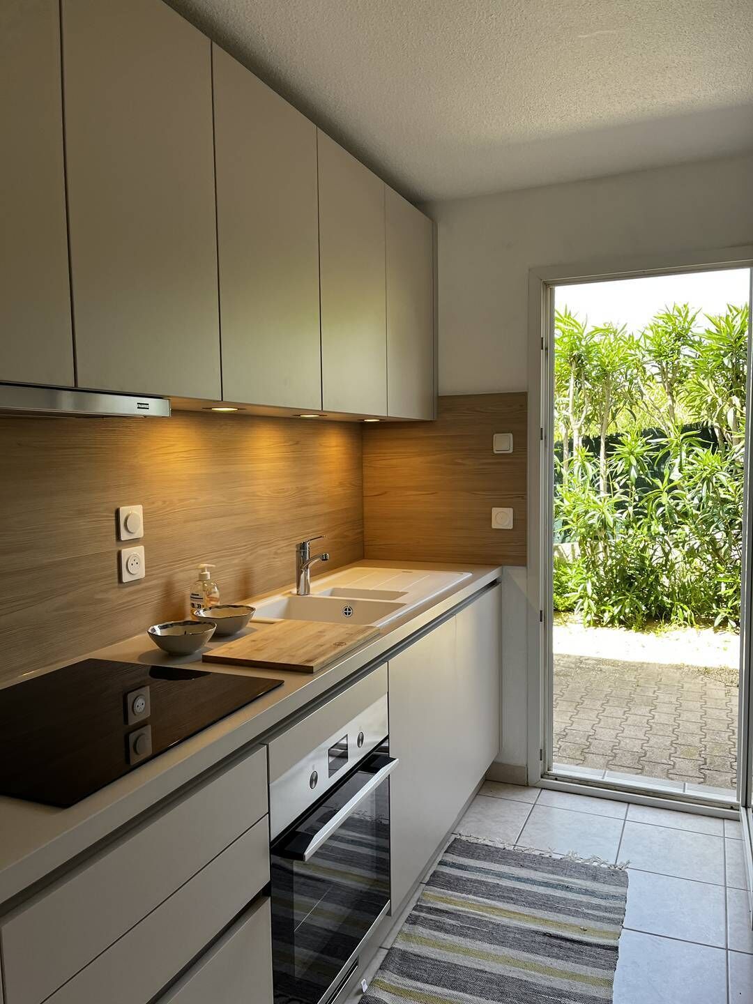 A modern kitchen with wooden cabinets, a black countertop, a sink, and an oven.