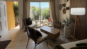 A modern living room with a view of the outdoors, a dining area, and a large window with curtains. - 2-Bedroom holidays Cottage with 2 Terrace, Air Conditioning  et  Parking (CANET PLAGE)