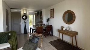 A spacious living room with a dining area, a large mirror, and a door leading to another room. - 2-Bedroom holidays Cottage with 2 Terrace, Air Conditioning  et  Parking (CANET PLAGE)