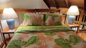 En säng med ett blommigt överkast, två sänglampor och en sänggavel i trä.