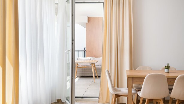 A modern hotel room with a wooden dining table, white chairs, and a view of a balcony. - Włochy Równoległa Cosy Apartment (Warszawa)