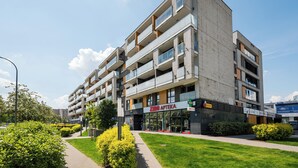 Een meerlaags gebouw met een modern architectonisch ontwerp, inclusief balkons en een winkelruimte op de begane grond.