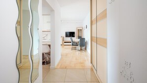 Een modern interieur met een eethoek, een televisie en een spiegel die de kamer weerspiegelt.
