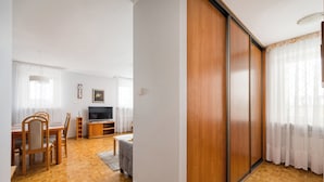 A living room with a TV, wooden furniture, and a sliding door. - National Stadium Spacious Apartment (Warszawa)