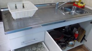 A kitchen with a stainless steel sink, a white countertop, and a drawer with glassware. - Complejo Turístico Holtfor  (Potrero de los Funes)