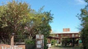 A gated entrance with a sign reading "Holt For Los Espinillos 434" and a building in the background. - Complejo Turístico Holtfor  (Potrero de los Funes)