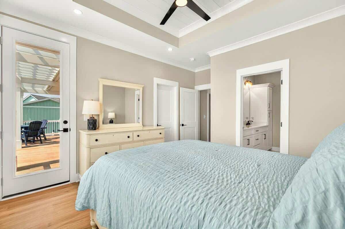 Un dormitorio con cama, cómoda y un espejo grande.
