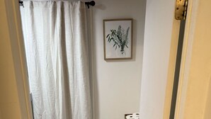 Un bany petit amb vàter, paperera i cortina de dutxa.