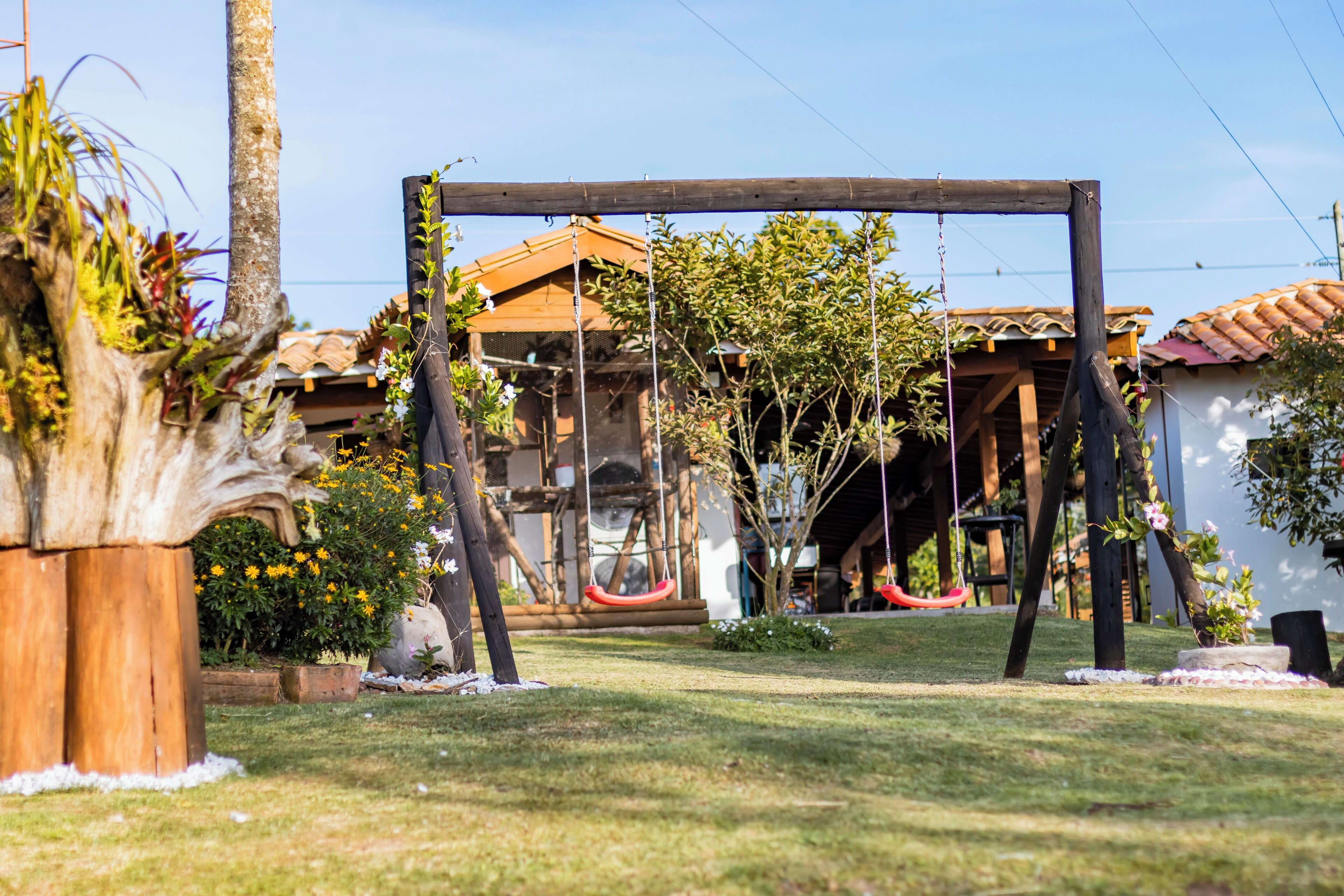 A wooden swing set in a garden with a house in the background.