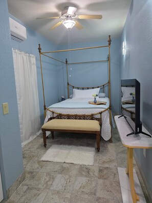 Relax in comfort with a four-poster bed and a bench at the foot, accompanied by a ceiling fan and a flat-screen TV.
