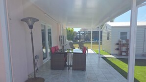 A covered patio area with a table and chairs, a floor lamp, and a view of the surrounding property. - Charming 1-bedroom apartment with WiFi and AC in delightful Port Charlotte (Port Charlotte)