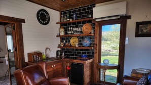 Uma sala de estar acolhedora com um sofá de couro, uma mesa de centro de madeira e uma área de cozinha com prateleiras embutidas.