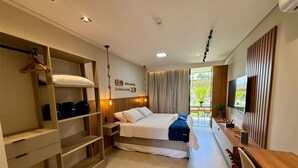 Een moderne hotelkamer met een bed, inbouwkast, nachtkastje en een televisie.