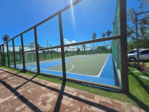 A basketball court enclosed by a fence with a clear blue sky above.