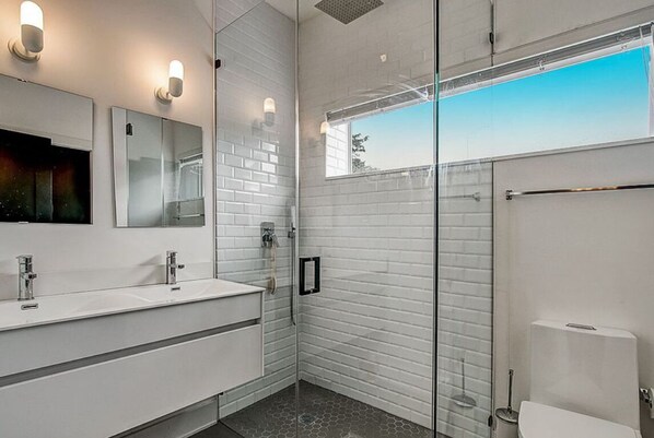 A modern bathroom with two sinks, a glass shower enclosure, and a toilet. - Elegant designer retreat in Miami Design District with luxe vibes (Miami)