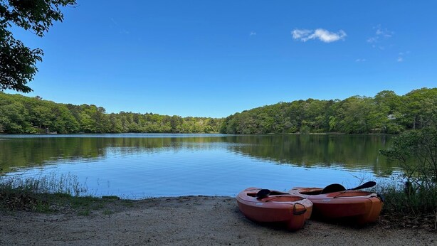 A calm lake with kayaks on the shore.