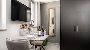 A modern dining area with a flat-screen TV, a large mirror, and a dark wardrobe.