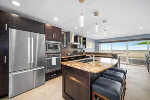 Prepare meals and socialize in this kitchen with an oven, microwave, and sink, offering a view of the beach.