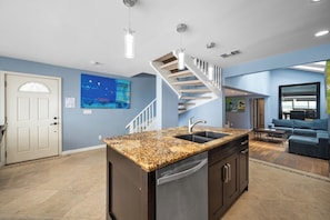 Enjoy a spacious kitchen with a granite countertop, stainless steel appliances, and a staircase leading to an upper level.
