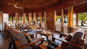 Una habitación amplia con muebles de madera, ventanas grandes y vistas a la playa.