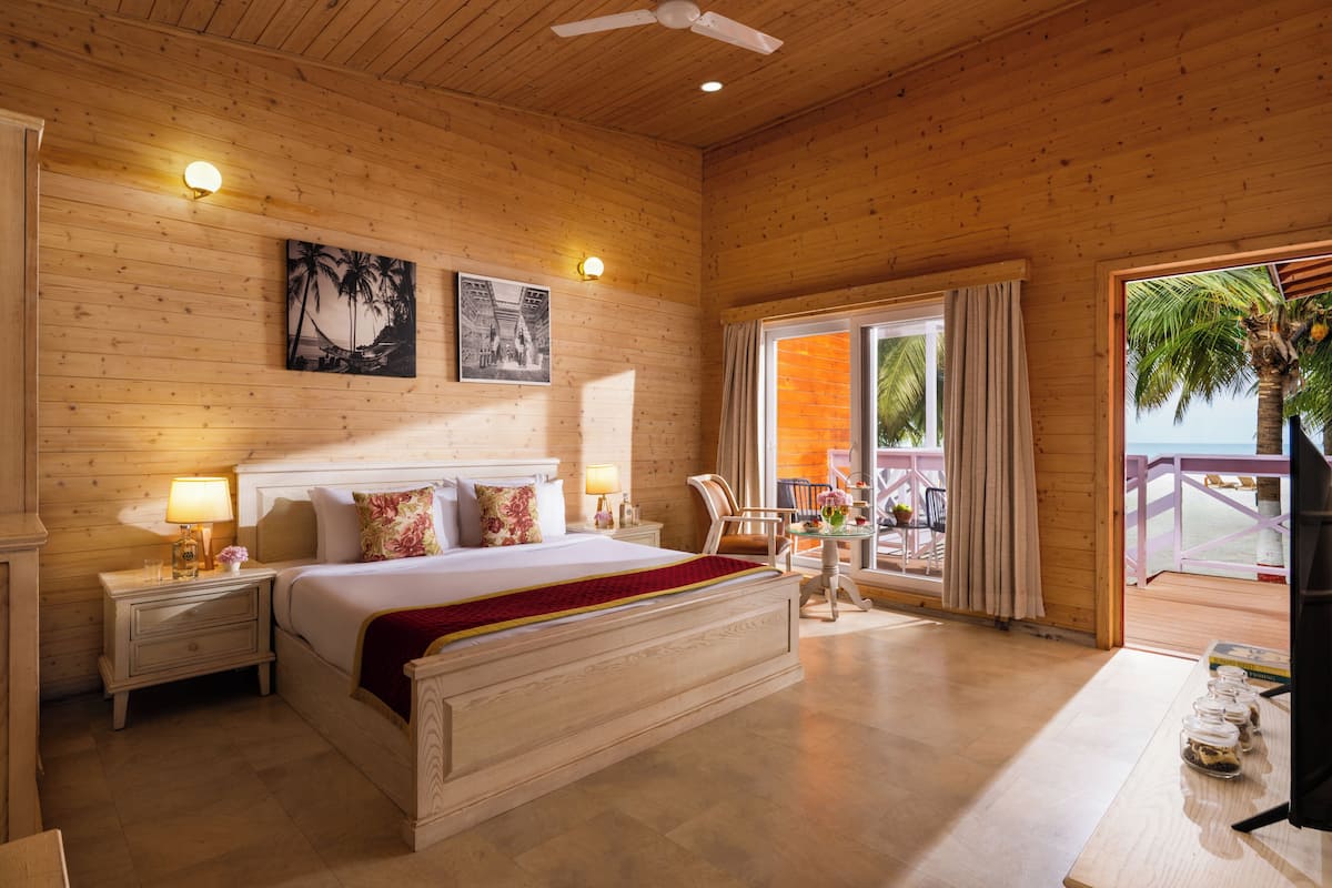 A wooden-paneled bedroom with a bed, nightstands, and a balcony with a view.