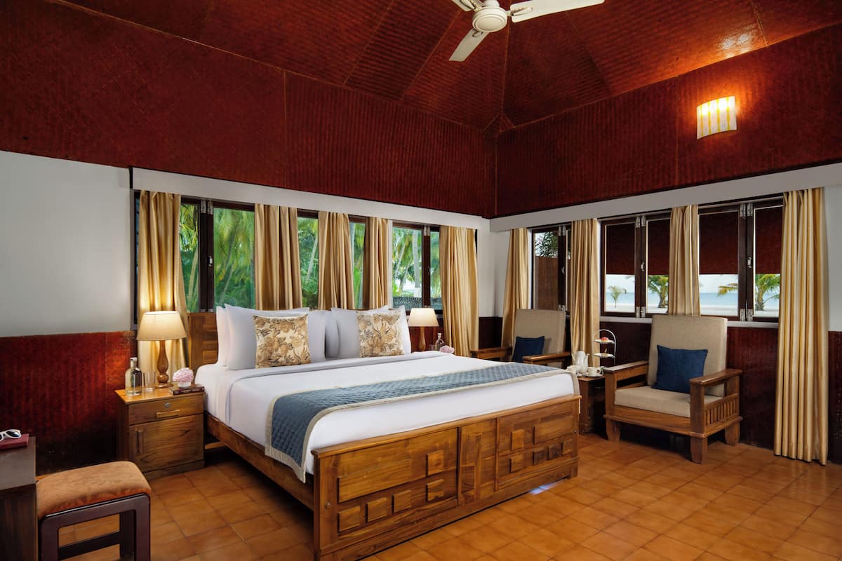 A spacious bedroom with a large bed, a ceiling fan, and a view of the beach through the windows.