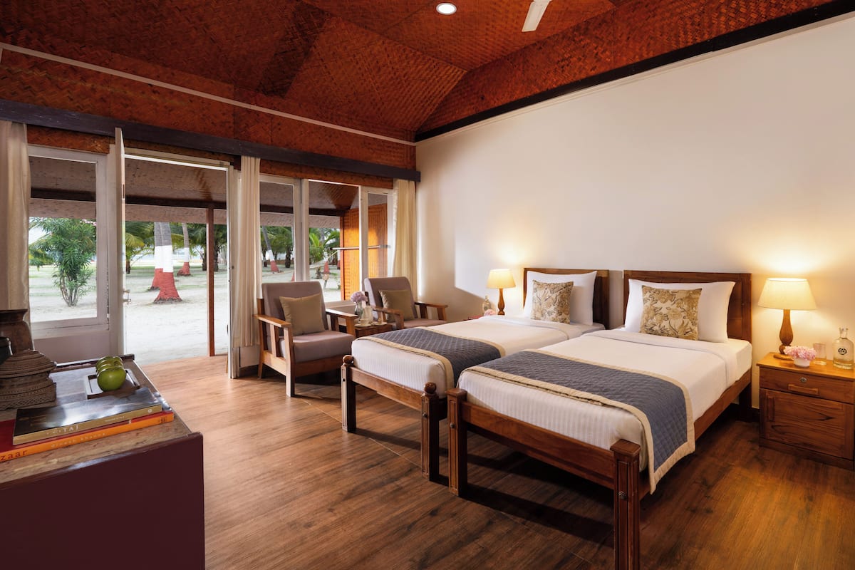 A hotel room with two beds, a desk, and a view of the outdoors.
