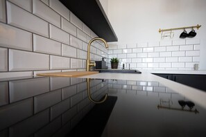 A modern kitchen with white subway tiles, a black backsplash, and a gold faucet.