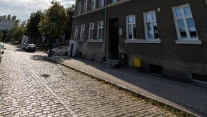 A multi-story building with a brick facade, large windows, and a cobblestone street. - Verde 1 Studio z Kuchni Wifi Dolny Gda sk (Gdansk)