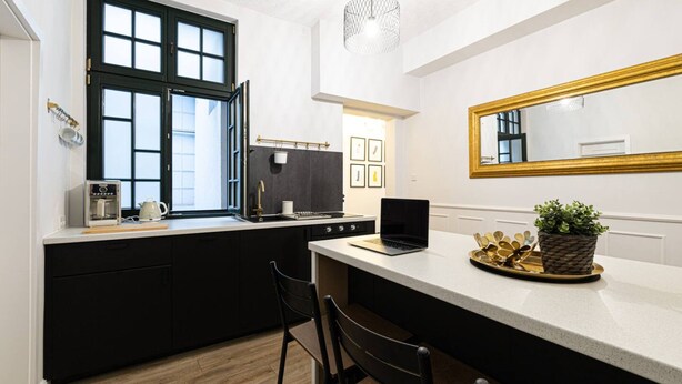 A modern kitchen with a large window, a laptop on the counter, and a potted plant. - Verde 1 Studio z Kuchni Wifi Dolny Gda sk (Gdansk)