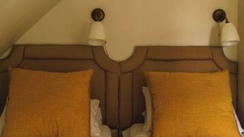 A room with two beds, each with a headboard and a pillow.