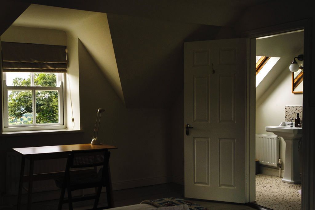 A room with a desk, chair, and a door leading to a bathroom.