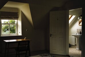 Una habitación con escritorio, silla y puerta que da a un baño.