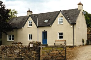 A two-story house with a blue door, a stone wall, and a wooden gate. - Belmont House (Cappoquin)