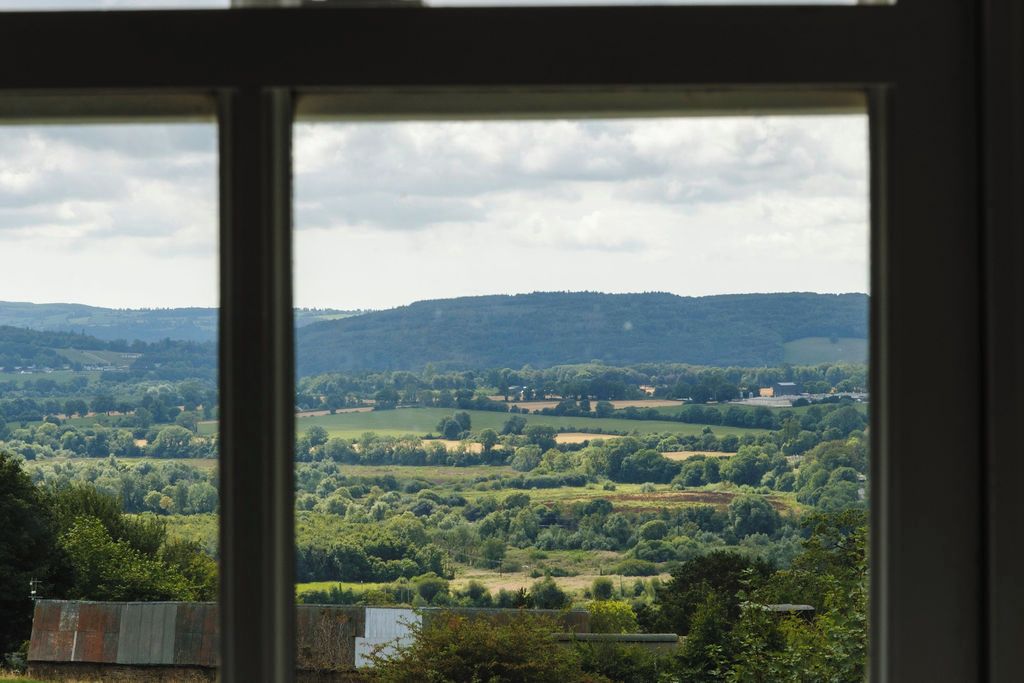 A view through a window of a landscape with rolling hills and scattered buildings.