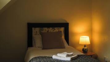 A hotel room with a bed, a nightstand with a lamp, and a window.